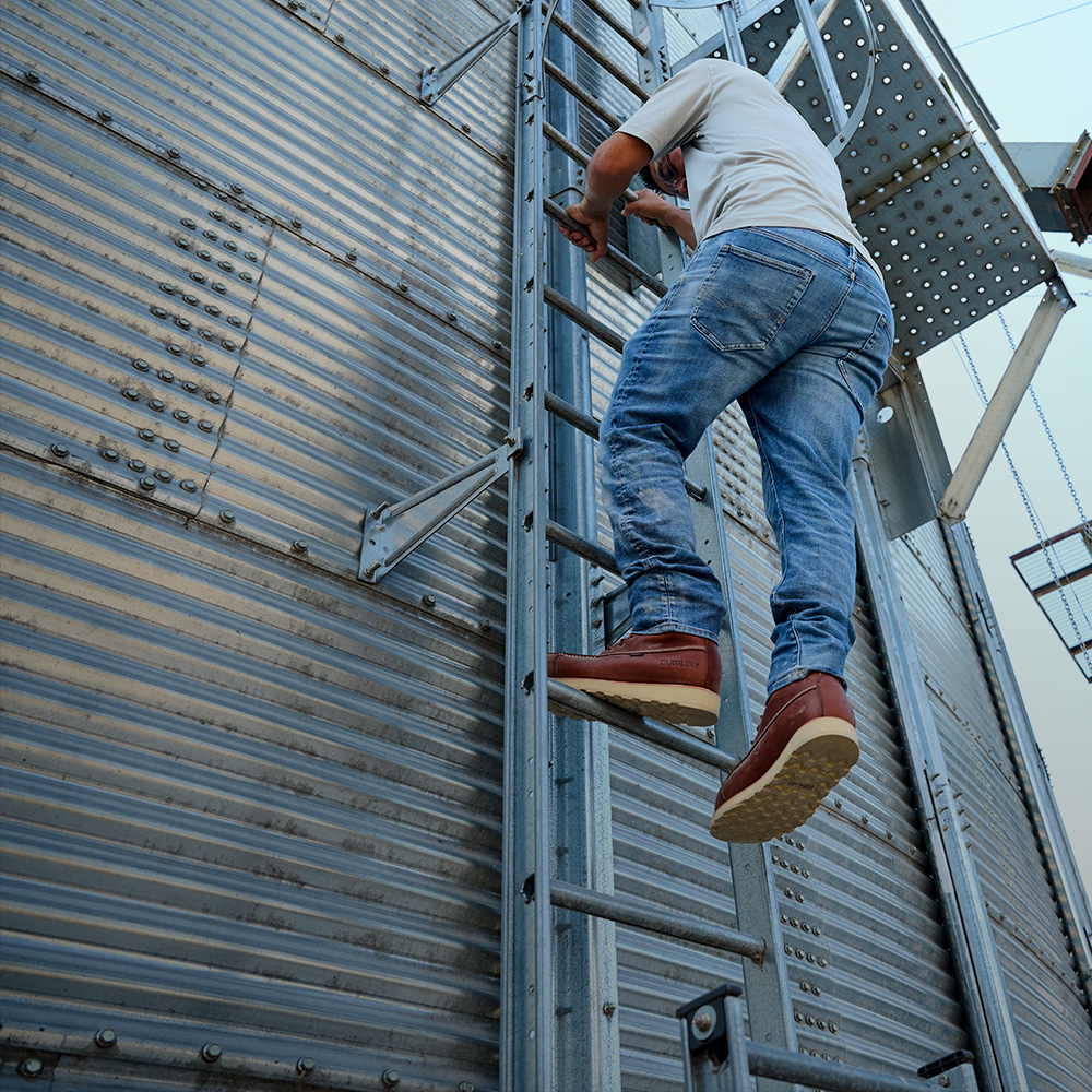 A man on a ladder wearing the Staple Gun 8" Carbon Comp Toe Waterproof Work Boot in brown.